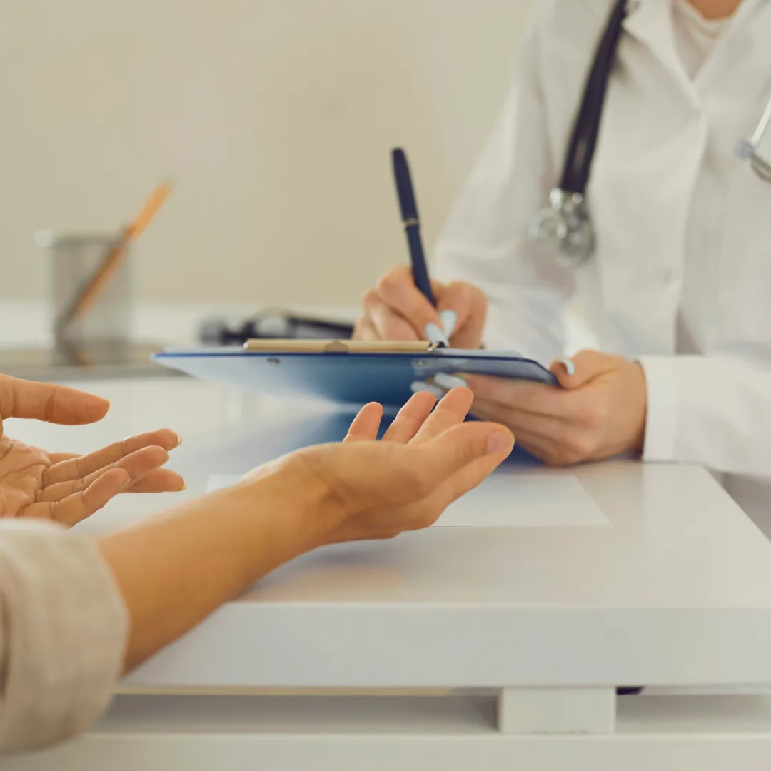Ärztin notiert Angaben einer Patientin