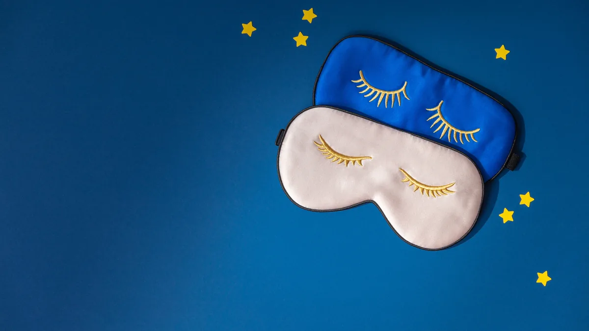 Schlafmaske mit geschlossenen Augen auf blauem Grund mit Sternen