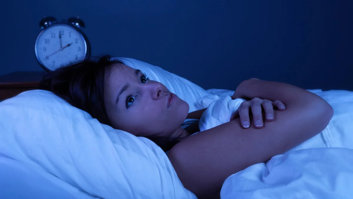 Frau liegt nachts wach im Bett