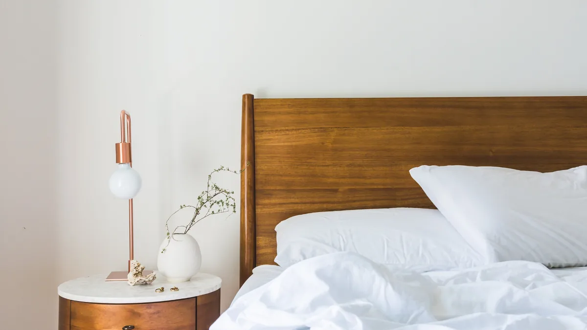Helles Schlafzimmer mit Holzbett und Nachttischlampe
