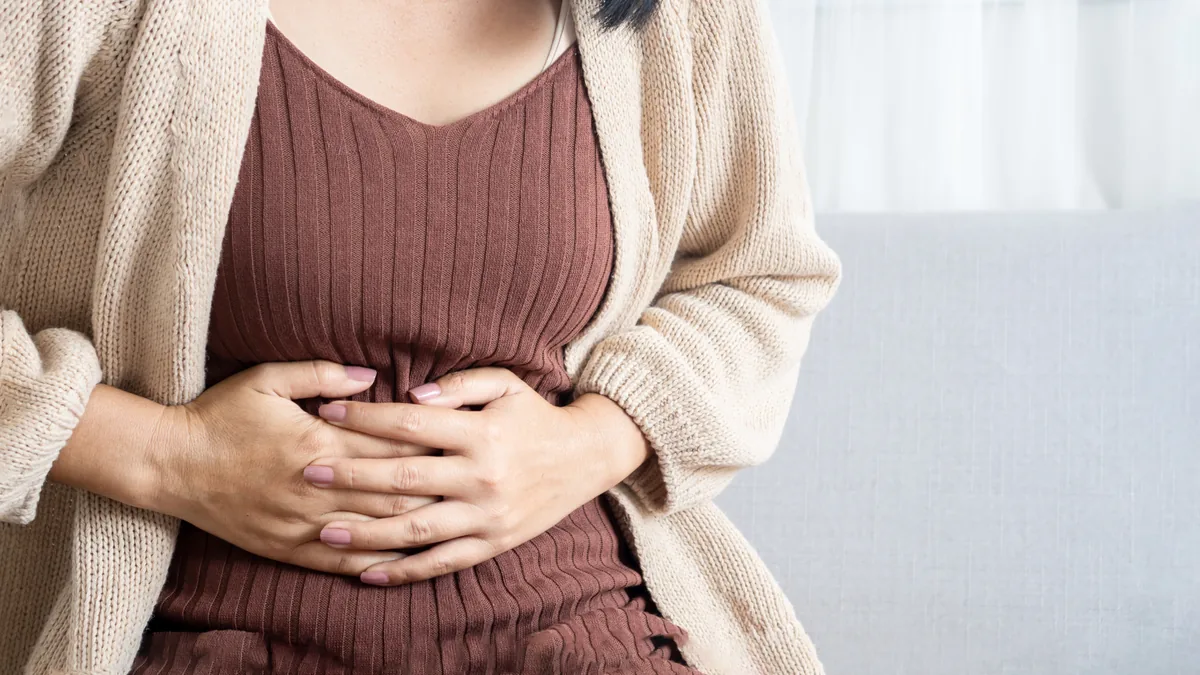 Frau legt die Hände auf ihren Bauch