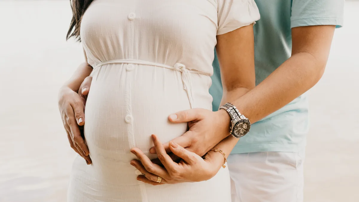 Paar legt die Hände auf einen Babybauch