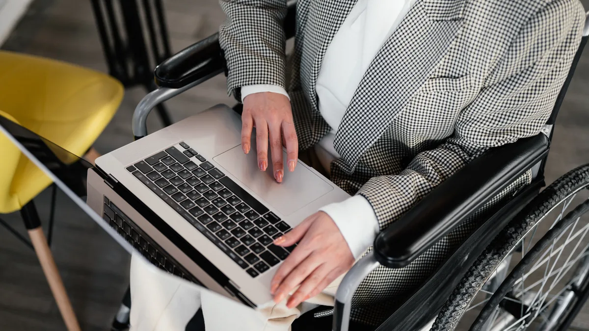 Person im Rollstuhl arbeitet am Laptop