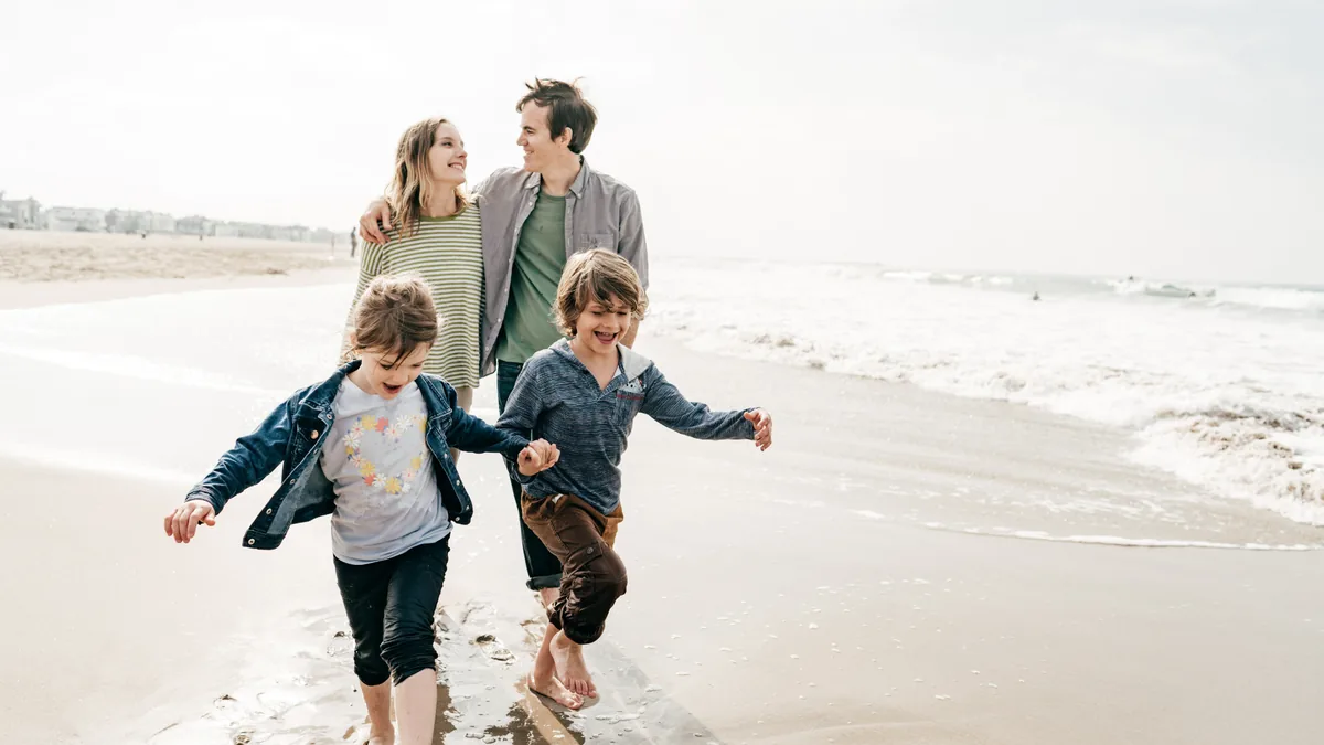 Familie läuft lachend am Strand