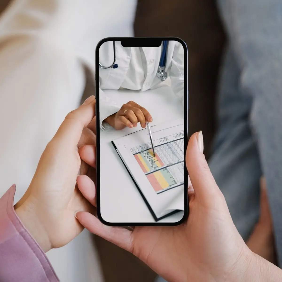 Hände halten ein Smartphone mit einer Videosprechstunde